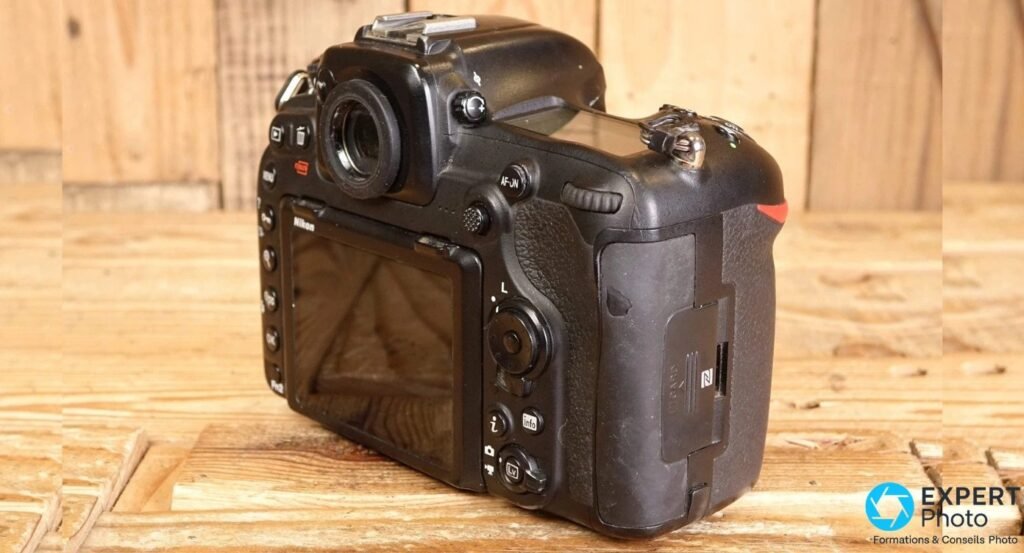 Dos d'un Nikon D500 en angle 3/4 avec écran LCD, joystick AF-ON et trappe carte latérale logo NFC.