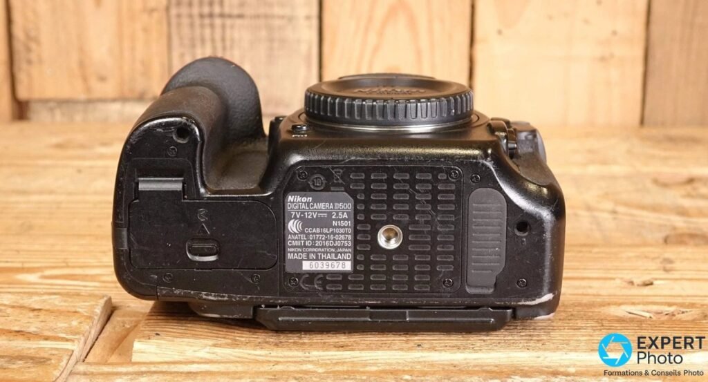 Dessous d'un Nikon D500 avec étiquette Nikon DIGITAL CAMERA D500, mention Made in Thailand et filetage trépied.