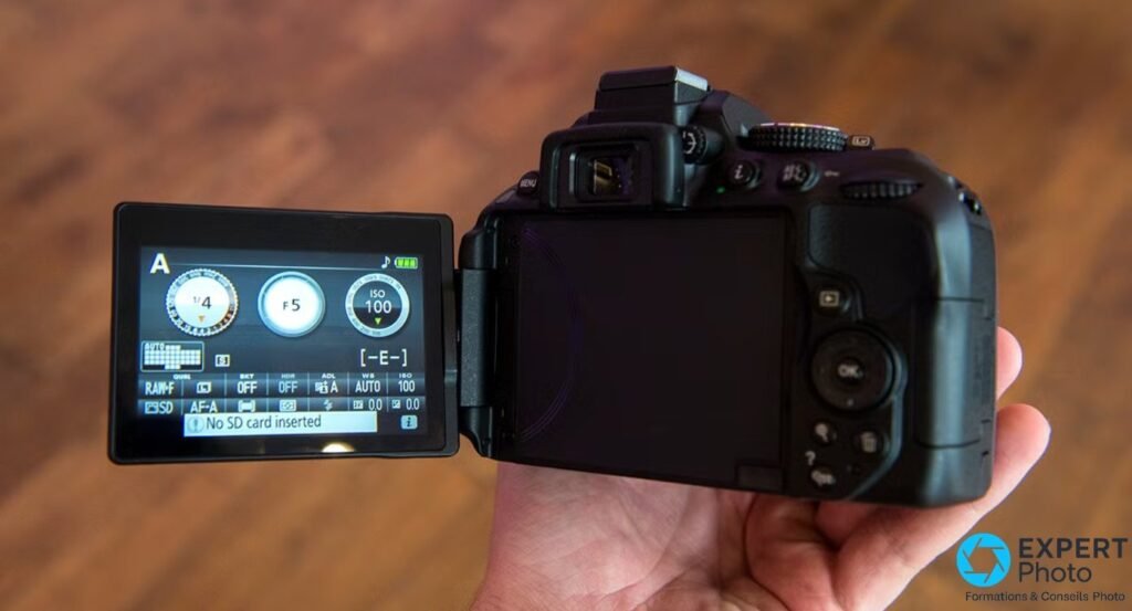 Vue arrière du Nikon D5300 avec écran orientable LCD déployé latéralement affichant les paramètres de prise de vue. 