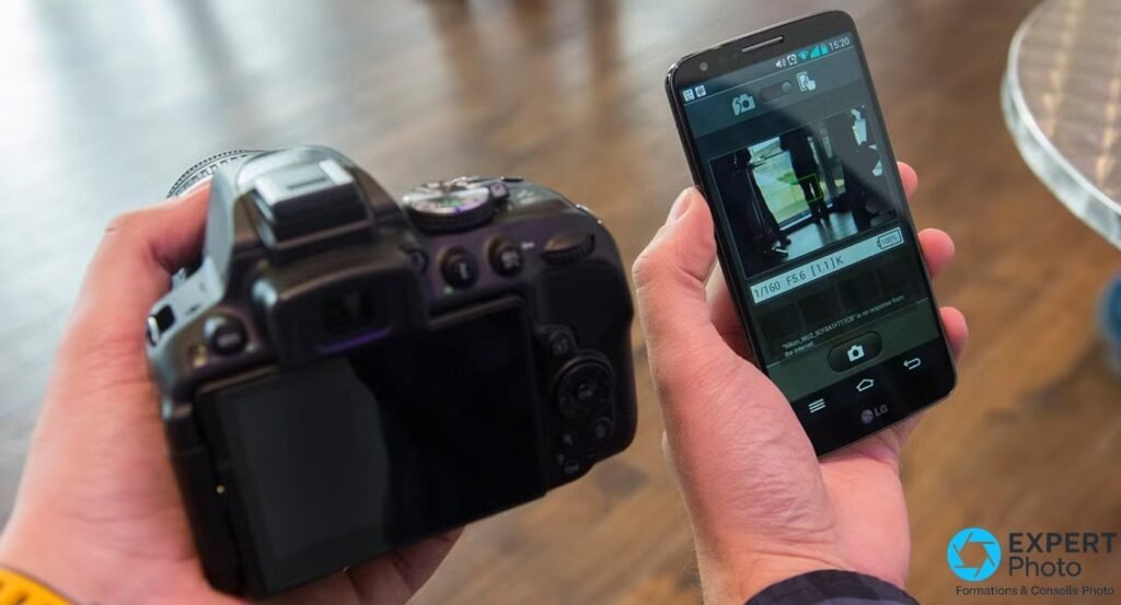 Nikon D5300 tenu en main vu de dos en communication Wi-Fi avec un smartphone LG affichant l'aperçu en direct du boîtier.