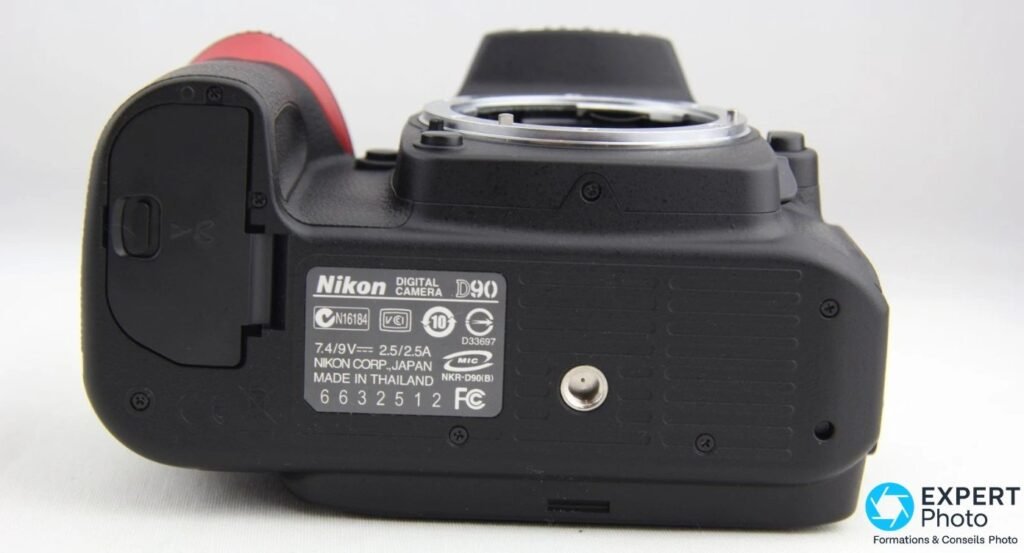 Dessous du Nikon D90 avec étiquette d’identification, trappe de batterie et pas de vis trépied 