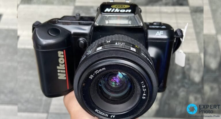 Reflex argentique Nikon F-401 tenu en main, vu de 3/4 face avec zoom AF Nikkor 35-70mm f/3.3-4.5 monté.