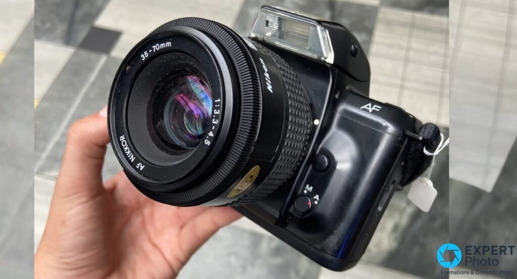 Nikon F-401 vu de 3/4 profil avec zoom AF Nikkor 35-70mm, flash escamotable replié et sélecteur M/A. 