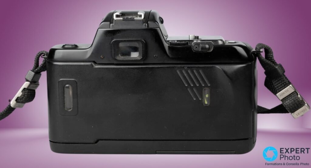 Dos du Nikon F-401s fermé, oculaire viseur, hot shoe vide et passants de sangle marqués Nikon visibles.