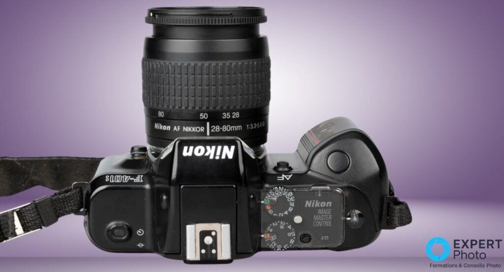 Nikon F-401s vu du dessus, objectif Nikon AF Nikkor 28-80mm et panneau Nikon Image Master Control visibles.