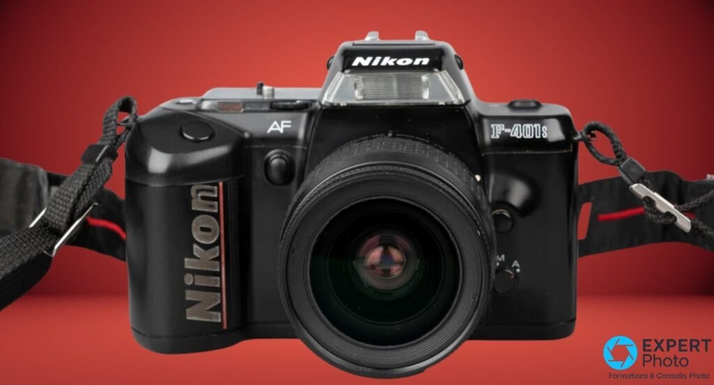 Nikon F-401s en vue frontale stricte avec objectif Nikon AF Nikkor 28-80mm monté, marquage F-401s visible. 
