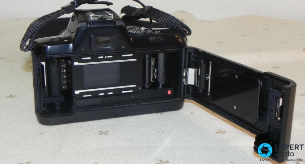 Nikon F-401x vue arrière trois quarts, dos ouvert, rail de guidage pellicule 35 mm et contacts DX visibles. 