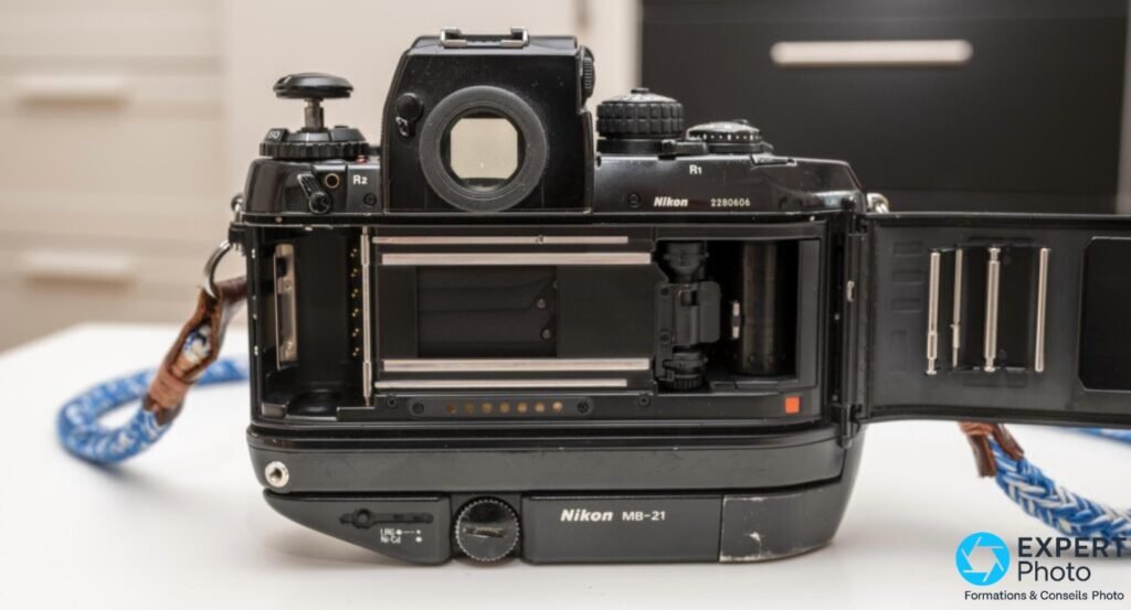  Nikon F4 dos ouvert : logement du film vide, rails et presseur visibles, poignée Nikon MB-21 dessous