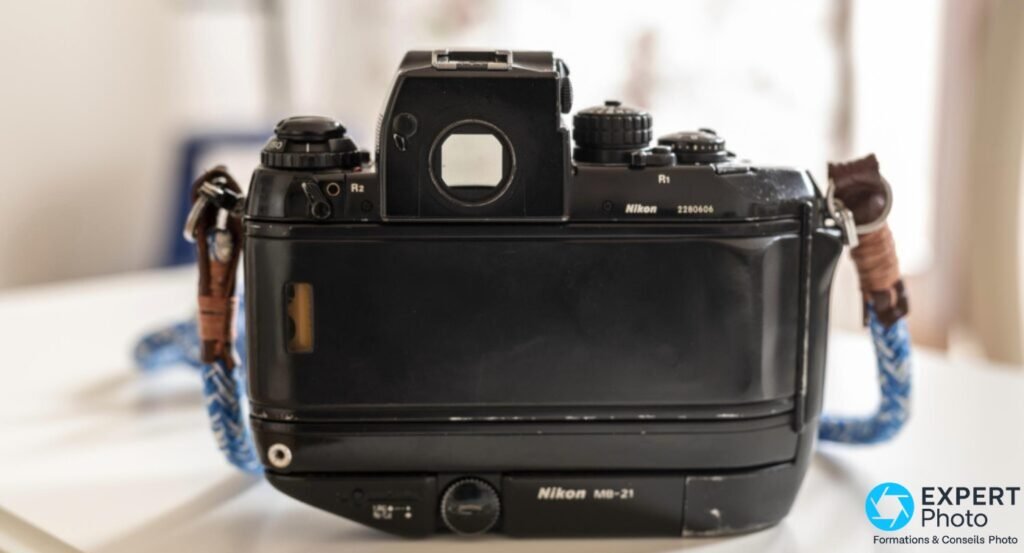 Dos du Nikon F4 noir, poignée Nikon MB-21, oculaire de visée, numéro de série gravé, dragonnes bleue et cuir 