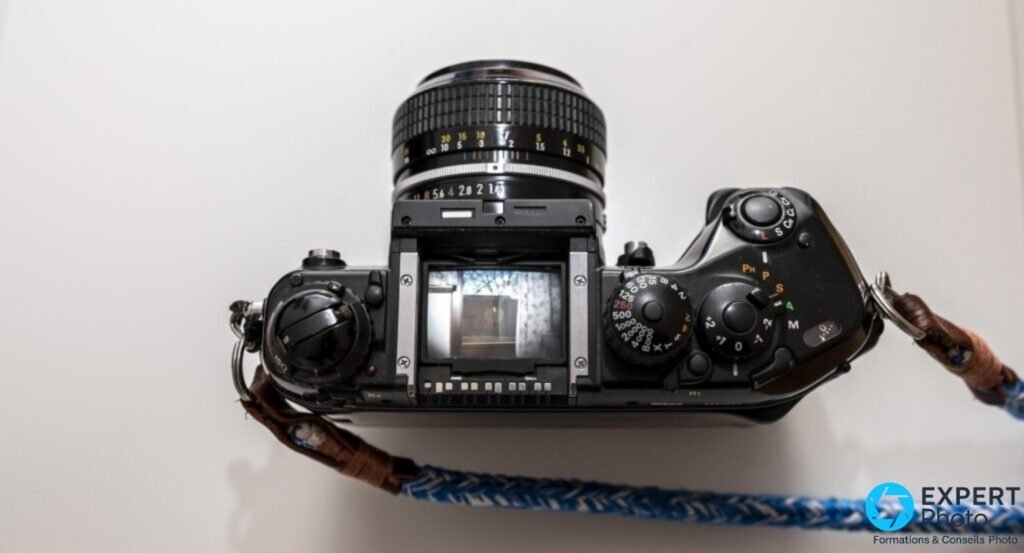 Nikon F4 vu de dessus, viseur prismatique retiré laissant voir le dépoli et la cage du miroir, objectif monté 
