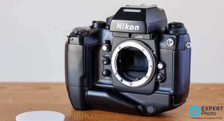 Nikon F4s : les 3 points qui décident l’achat d’occasion Nikon F4s vu de face avec grip MB-21 et prisme DP-20, monture Nikon F sans objectif, cap Nikon posé en bas à gauche