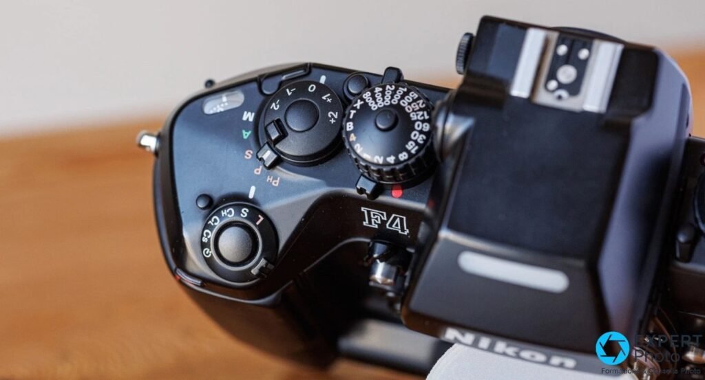 Top du Nikon F4s vu de côté avec le logo F4 gravé, la marque Nikon et l'ensemble des molettes mécaniques