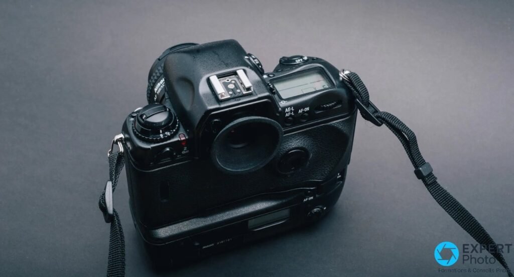 Nikon F5 vu de l'arrière trois quarts sur fond gris studio, œilleton de viseur, écran LCD arrière, boutons AE-L AF-ON
