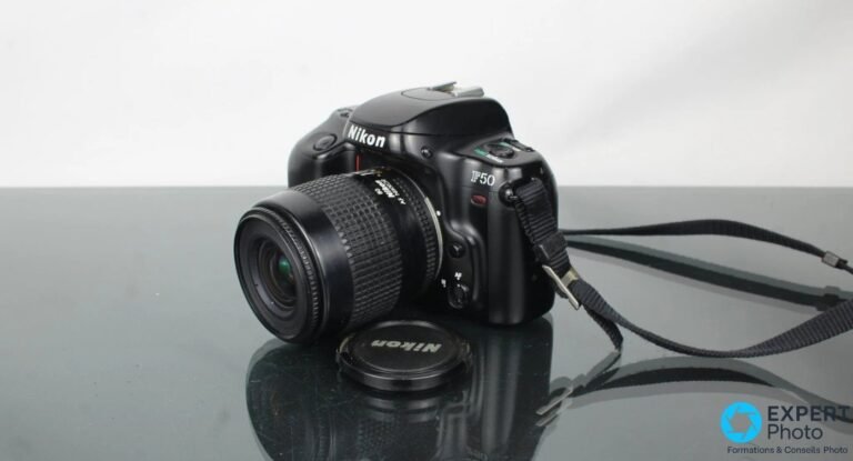 Nikon F50 : ce que vaut vraiment ce reflex argentique d’occasion Nikon F50 de trois quarts avant, objectif zoom AF Nikkor lentille avant visible, bouchon Nikon pose devant.