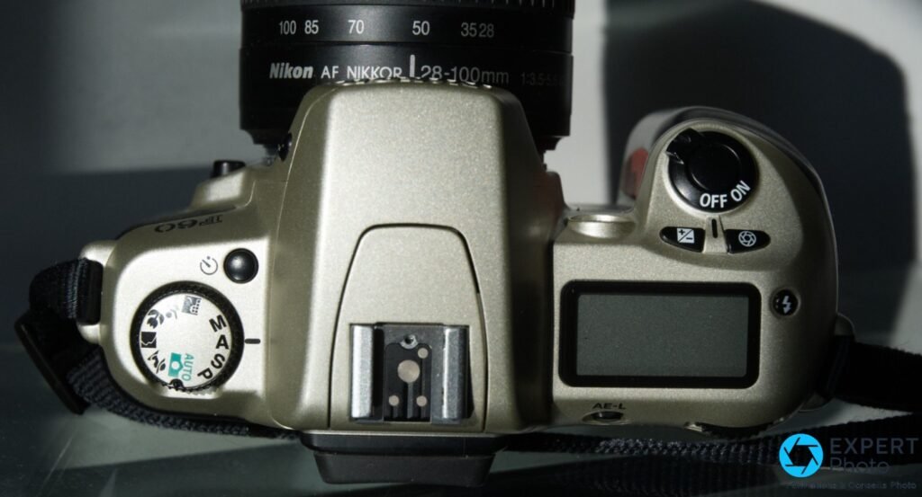 Nikon F60 vue de dessus, molette AUTO/P/S/A/M, griffe flash, écran LCD et bague objectif AF Nikkor 28-100mm lisible