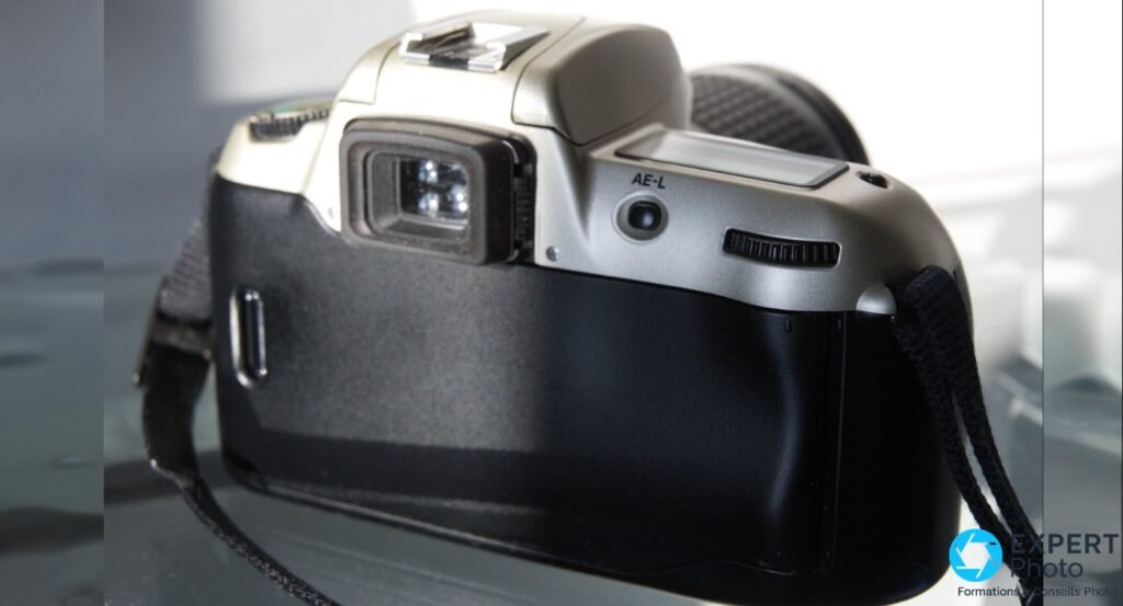 Nikon F60 vu de l’arrière, viseur optique en caoutchouc, inscription AE-L, flash relevé, boîtier champagne et noir