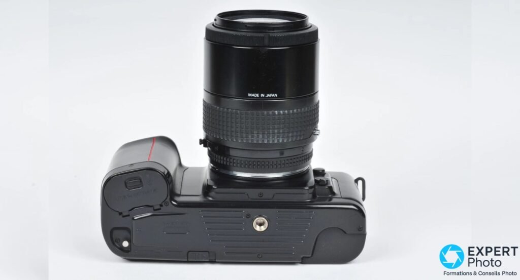 Nikon F-601 vu par le dessous, vis de pied centrale, zoom AF Nikkor monté avec inscription Made in Japan