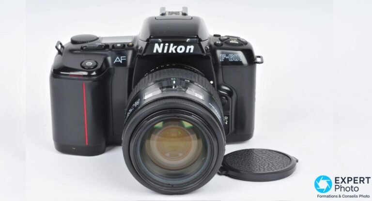 Nikon F-601 noir de face avec zoom AF monté, bouchon d'objectif posé au premier plan, fond blanc