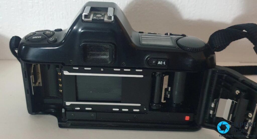 Nikon F-601M dos ouvert : compartiment film vide à gauche, axe de chargement à droite, viseur et bouton AE-L visibles