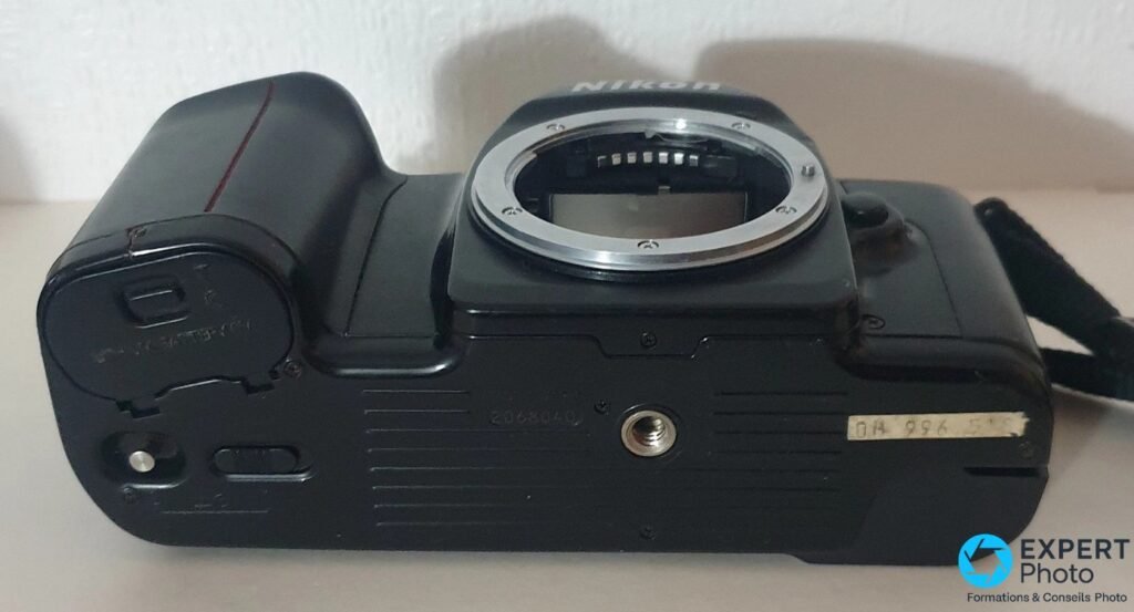 Semelle du Nikon F-601M : cache pile à gauche, filetage trépied central, numéro de série gravé sur le boîtier