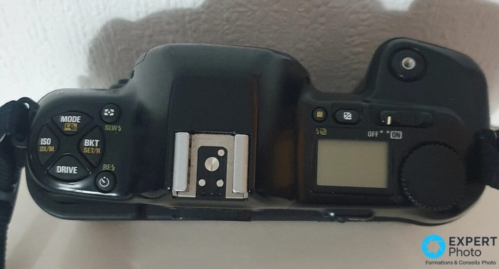 Capot du Nikon F-601M vu du dessus, commandes MODE, ISO, BKT, DRIVE, sabot griffe-flash et écran LCD visibles