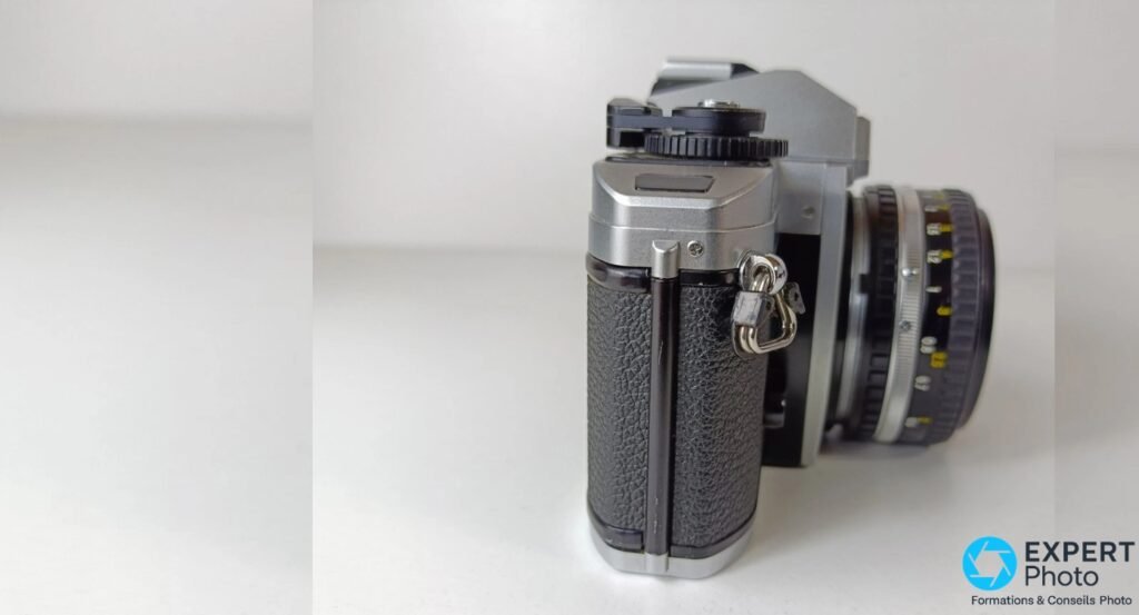 Nikon FG-20 vu de profil droit, boîtier nu sans objectif, anneau d'attache sangle et griffe flash visibles