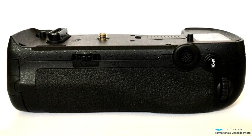 Grip Nikon MB-D18 vu de profil droit, avec bouton AF-ON et interrupteur LOCK sur la tranche, fond blanc