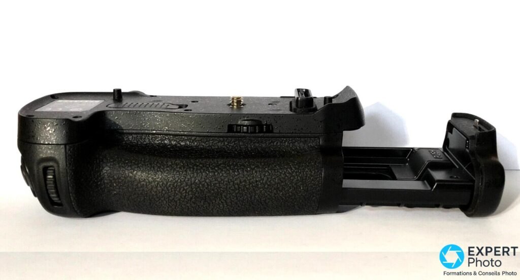 Grip Nikon MB-D18 de profil gauche, trappe du compartiment batterie pivotée ouverte révélant le logement vide 