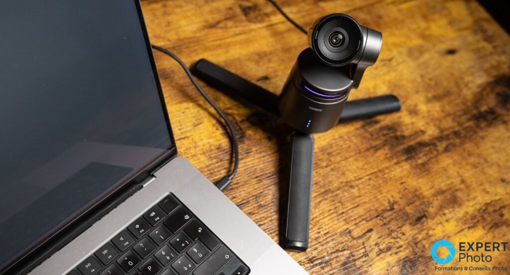 OBSBOT Tail Air sur trépied de table à côté d’un ordinateur portable, câble USB reliant la caméra à l’ordinateur