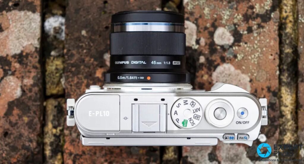 Olympus PEN E-PL10 vu de dessus, marquage E-PL10, molette de modes A/S/M/P/ART/AUTO et objectif M.Zuiko 45 mm