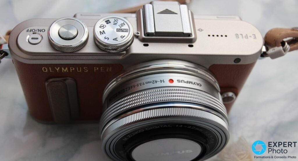  Olympus PEN E-PL8 brun vu de 3/4 dessus, marquage E-PL8 et OLYMPUS PEN, molettes, objectif 14-42mm EZ