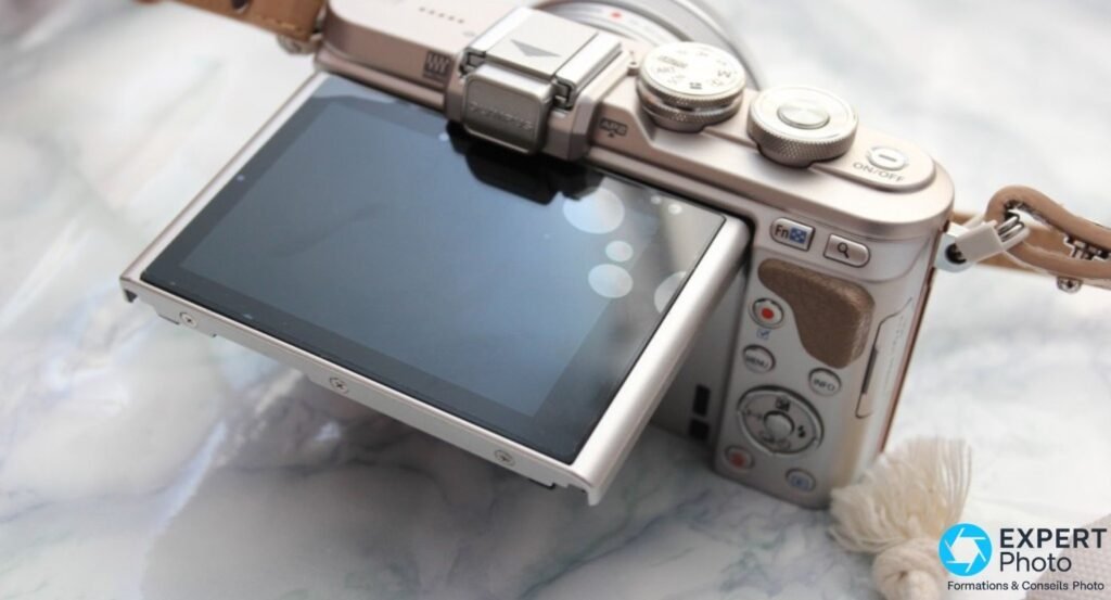 Olympus PEN E-PL8 vue arrière 3/4, écran orientable basculé vers le haut à 180° pour selfies 
