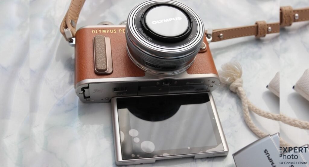  Olympus PEN E-PL8 brun, dessous avec trappe ouverte, objectif 14-42mm, écran rabattu, accessoire OLYMPUS