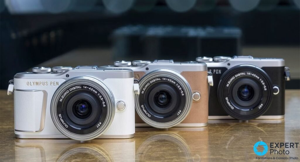 Trois Olympus PEN E-PL9 alignés, coloris blanc, marron et noir, avec objectif 14-42mm sur chaque.