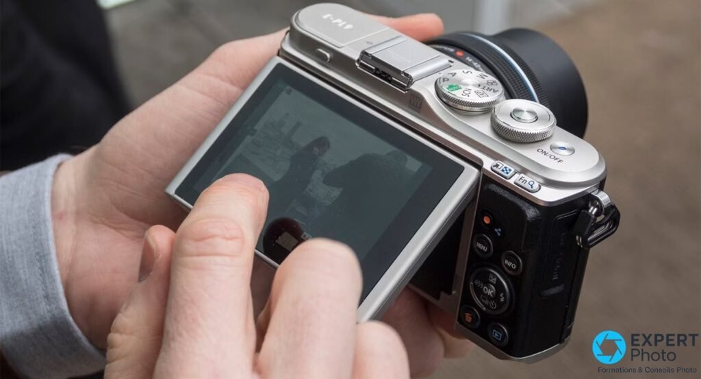  Olympus PEN E-PL9 vu de dos en prise en main, doigt qui interagit avec l'écran tactile arrière.