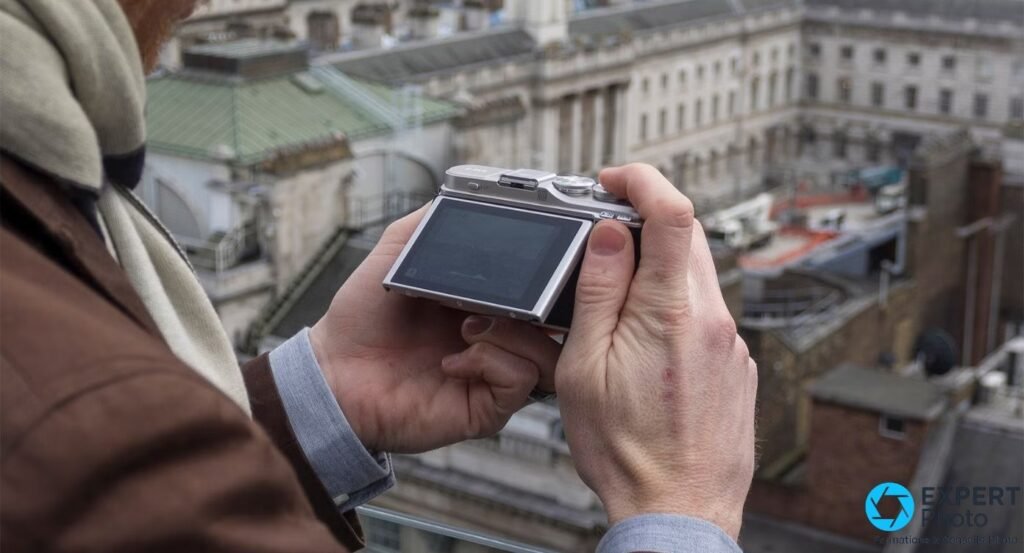 Olympus PEN E-PL9 argenté tenu à deux mains, vue arrière avec écran, en extérieur surplombant Londres.