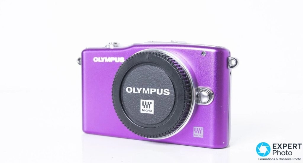 Olympus PEN E-PM1 finition violette en 3/4 avant, capuchon de monture Olympus Micro Four Thirds monté