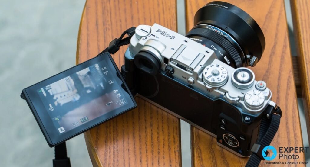 Olympus PEN-F vu de dessus avec écran orientable déployé affichant le live view, M.Zuiko 17mm et pare-soleil 