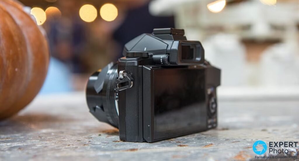 Olympus Stylus 1 vu de trois-quarts arrière, écran arrière replié, viseur électronique et molette de correction dioptrique. 