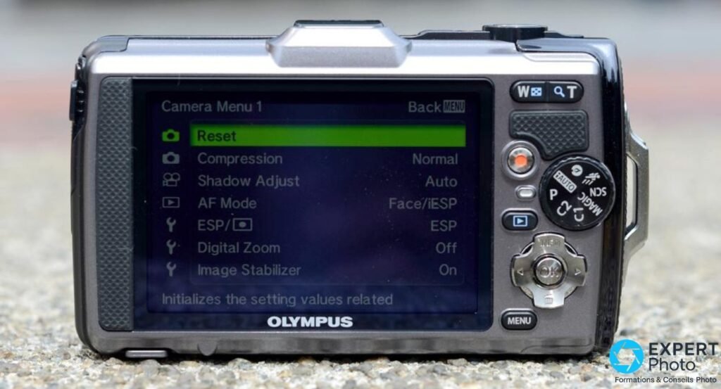 Olympus Tough TG-1 vu de dos : écran LCD allumé sur Camera Menu 1, roue de mode et navigation directionnelle visibles.