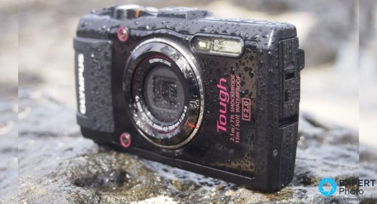 Olympus Tough TG-4 noir vu de 3/4 avant, boîtier mouillé avec gouttes d'eau, posé sur une roche grise