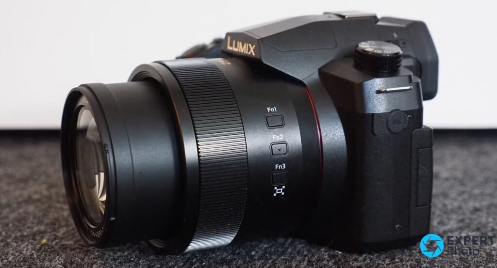 Panasonic Lumix FZ1000 II vu de 3/4 droit, zoom étendu avec liseré rouge, boutons Fn1 Fn2 Fn3 visibles