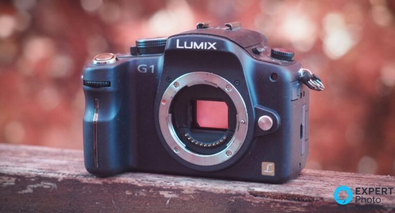 Panasonic Lumix G1 de face, boîtier noir sans objectif, monture micro 4/3 nue et capteur visible, fond bokeh chaud.