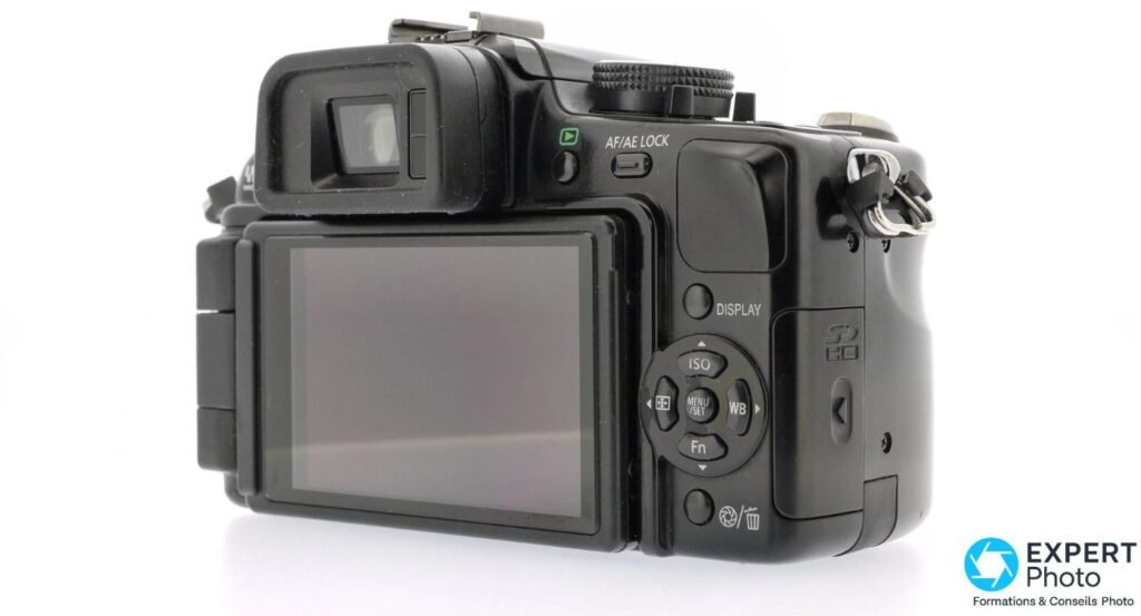 Panasonic Lumix G1 en trois quarts arrière, écran orientable déployé sur le côté, fond studio blanc.