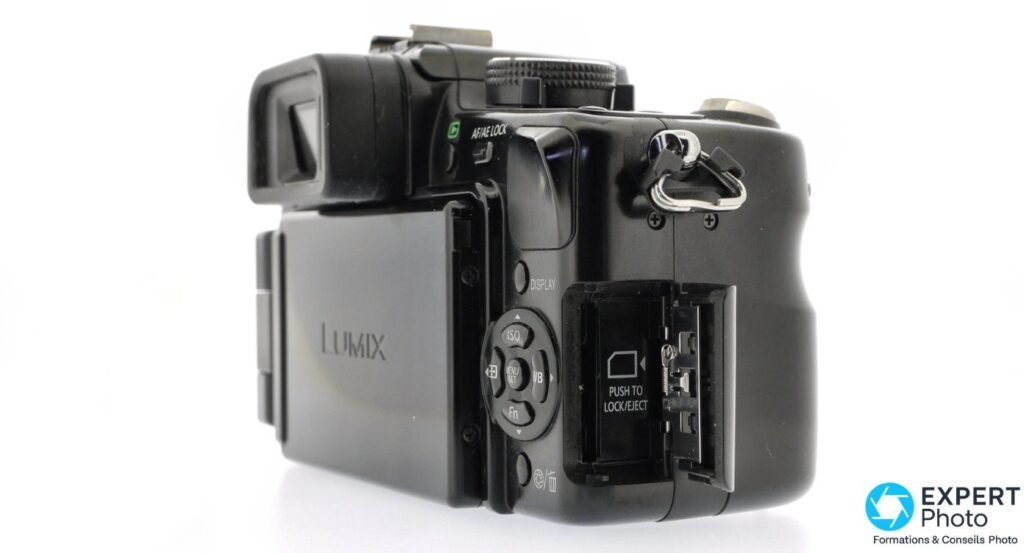 Panasonic Lumix G1 trois quarts arrière, trappe carte SD ouverte, écran orientable replié contre le boîtier. 