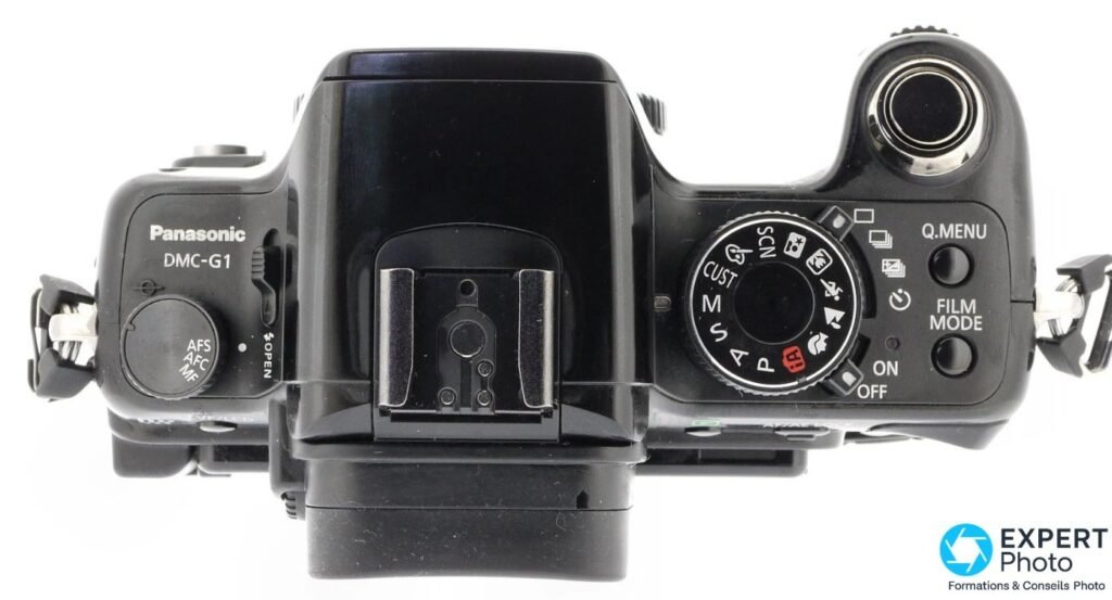 Panasonic Lumix G1 vu de dessus, molette de modes M/S/A/P/SCN, griffe porte-flash, sélecteur AFS/AFC/MF. 