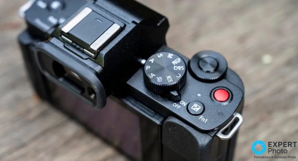 Panasonic Lumix G110 / G100 vu en plongée : molette de modes, bouton REC rouge et switch ON/OFF visibles sur le dessus. 