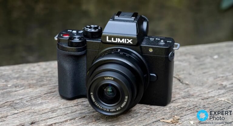 Panasonic Lumix G110 / G100 hybride Micro 4/3 vu de 3/4 avant avec l'objectif Lumix G Vario 12-32 mm posé sur planche bois.