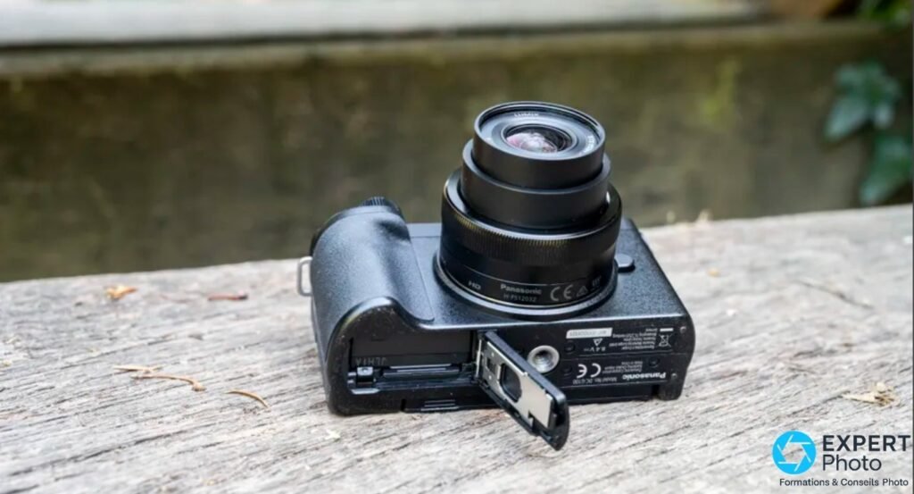 Panasonic Lumix G110 / G100 vu de dessous, trappe batterie ouverte, gravures Panasonic Model No. DC-G100 visibles.