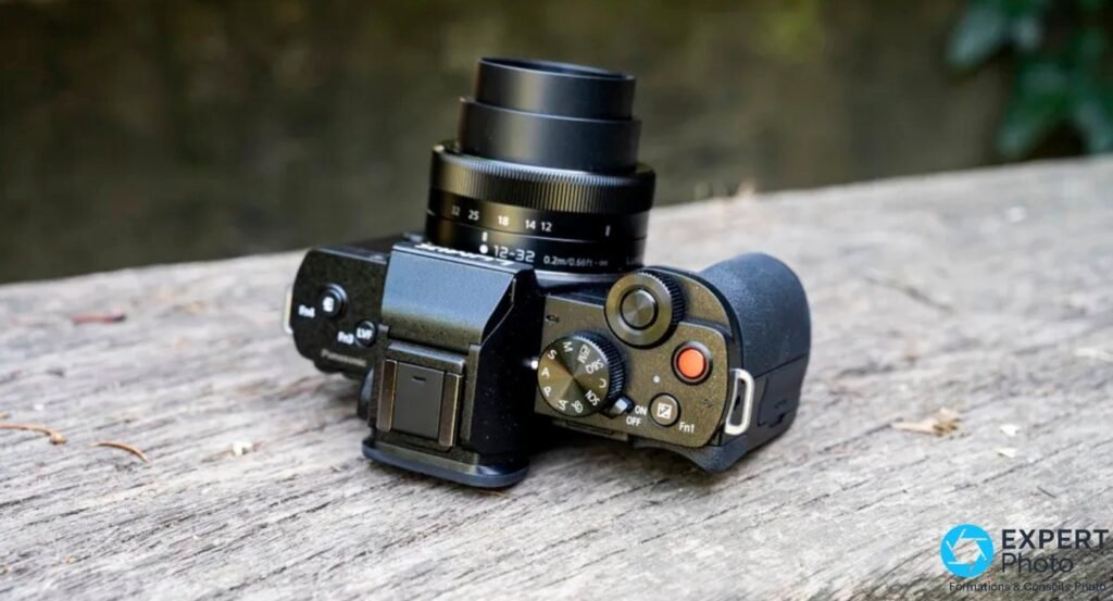  Panasonic Lumix G110 / G100 vu de dessus, objectif Lumix G 12-32 mm en extension et commandes du dessus visibles.